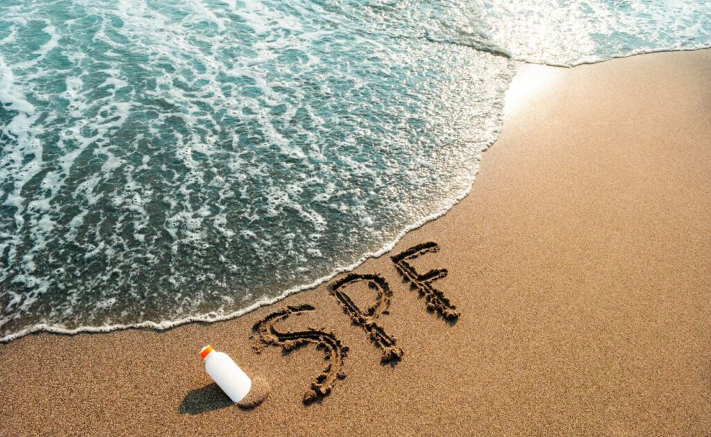 Beach scene with various sunscreen products: UV filters. SPF on sand and water background