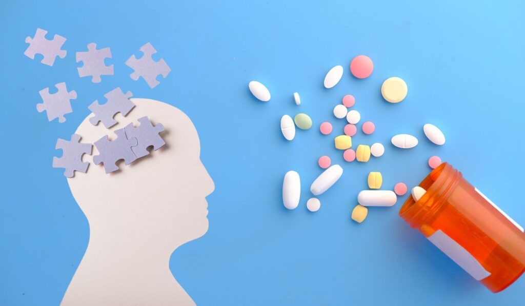 A conceptual image depicting a fragmented human head with scattered puzzle pieces, symbolizing mental health struggles. Next to the head, various psychotropic tablets are displayed, representing the complexity of mental health treatment. This image highlights the importance of understanding the regulations surrounding psychotropic medications in Poland, where nearly 5% of the population has used such medications within the last year. Key themes include mental health awareness, the role of psychotropic drugs, addiction risks, and the significance of proper prescription practices.